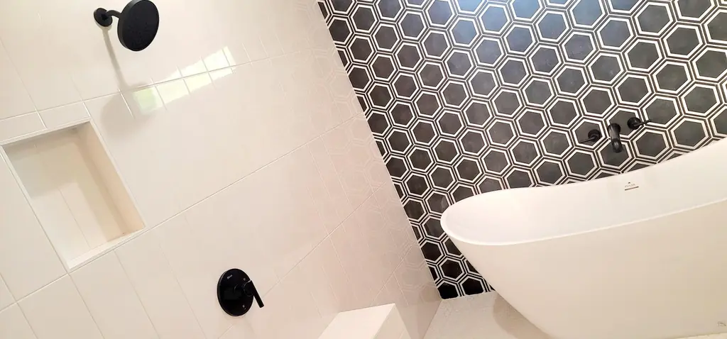 Black hex tile shower beside a freestanding tub