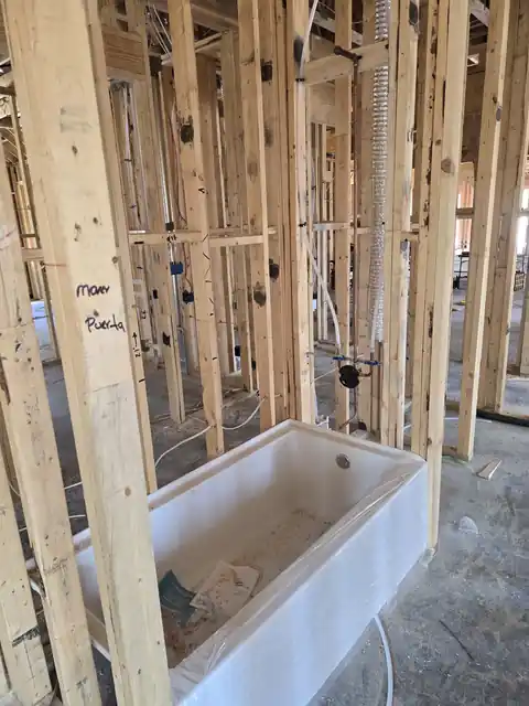Bathtub set in place inside wall framing on a new-construction job