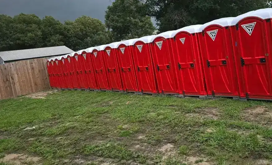 A row of red PrimeTime portable toilets, each stamped with the white triangle logo