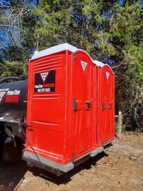 Red portable toilets loaded on a branded trailer