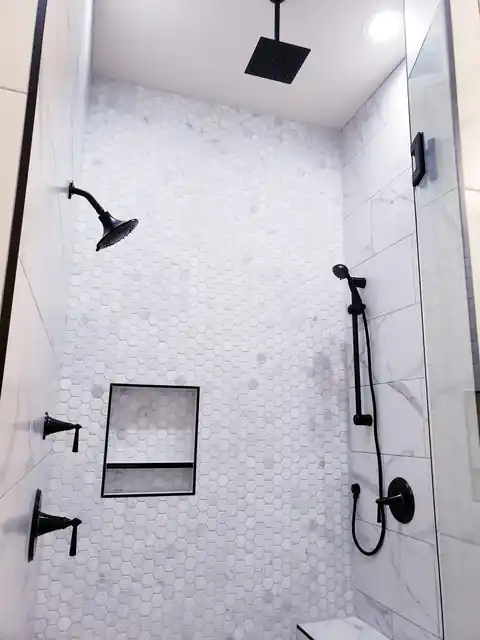 Marble shower with black fixtures and a recessed niche