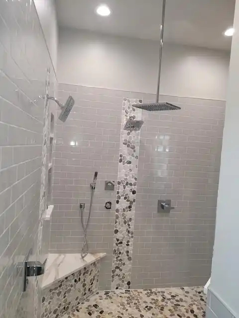 Walk-in shower with a strip of pebble tile along the floor