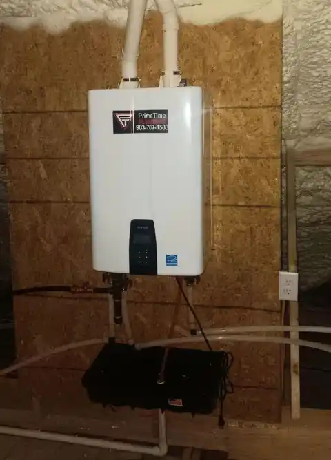Tankless water heater mounted on a new-construction wall with a PrimeTime sticker