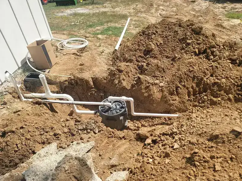 Trench with a new line running beside a house, dirt piled along the edge
