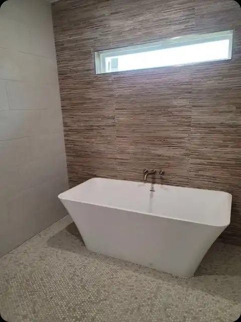 Freestanding tub in front of a stone feature wall