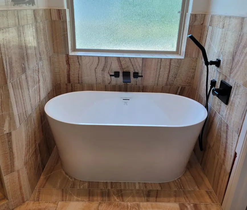 Freestanding tub against a wood-look tile wall with a wall-mounted filler
