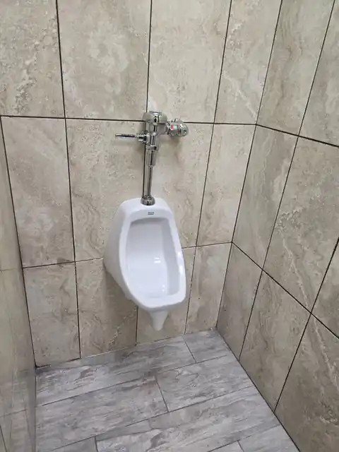 Commercial urinal installed on a tiled restroom wall